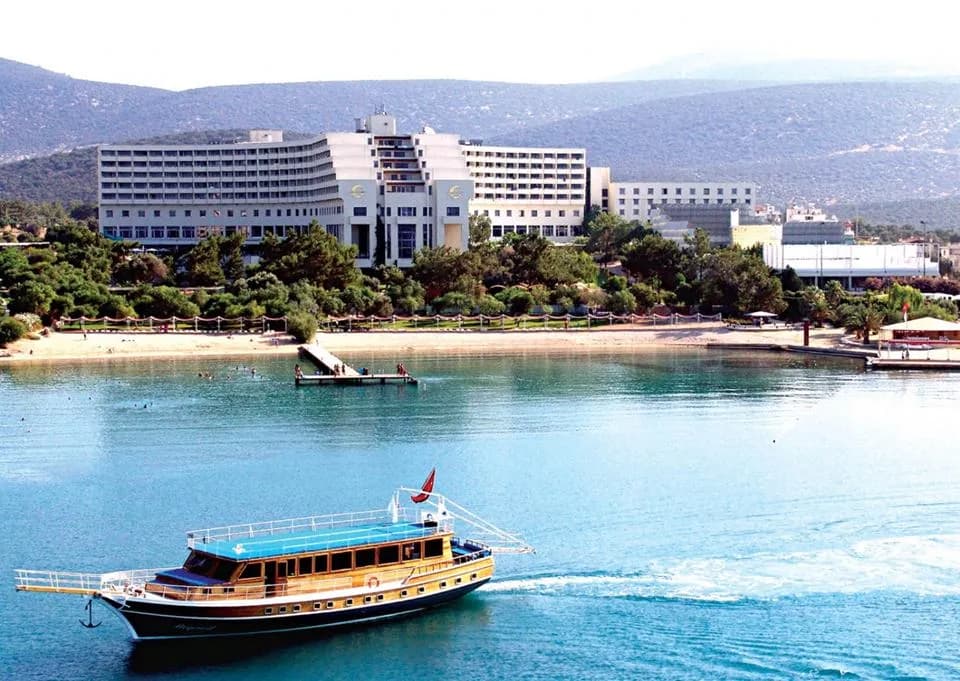 Caprice Otel'in sahil cephesi; önde koyda gezi teknesi