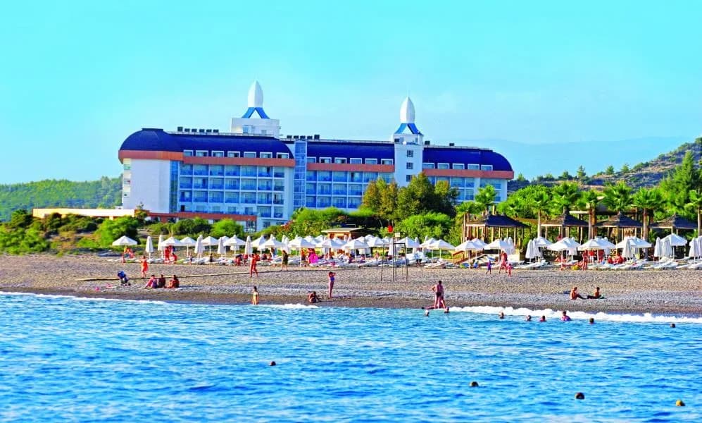 Nilbahir Hotel'in çakıl plajı ve mavi-beyaz ana binası