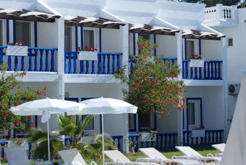 Royal Sunshine Hotel'in mavi-beyaz balkonlu cephesi ve şemsiyeli terası