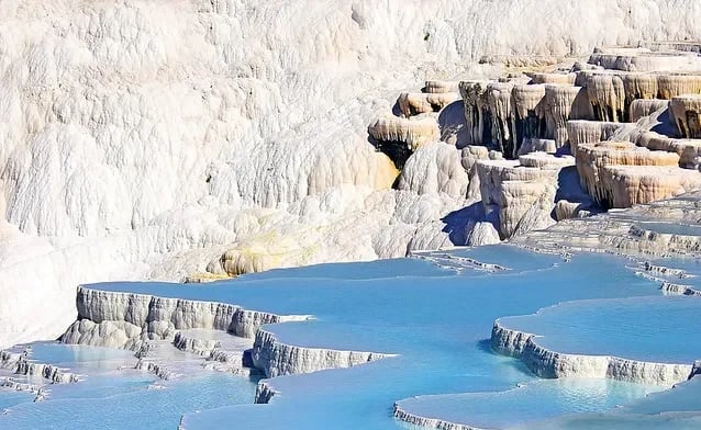 Pamukkale travertenlerine yukarıdan bakış: kat kat beyaz teraslar ve mavi su birikintileri