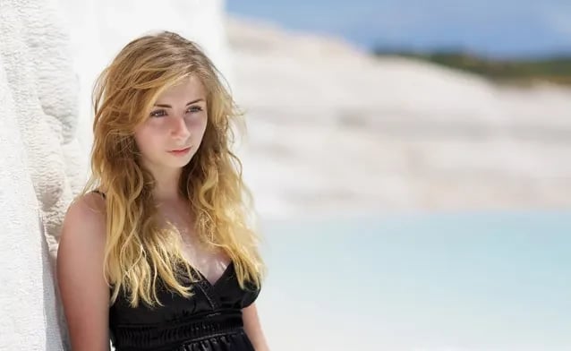 Pamukkale travertenleri önünde poz veren bir ziyaretçi; arka plan bulanık beyaz teraslar