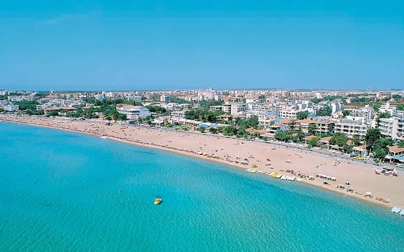 Çeşme sahili: uzun kumsal, turkuaz deniz ve şehir silüeti, havadan
