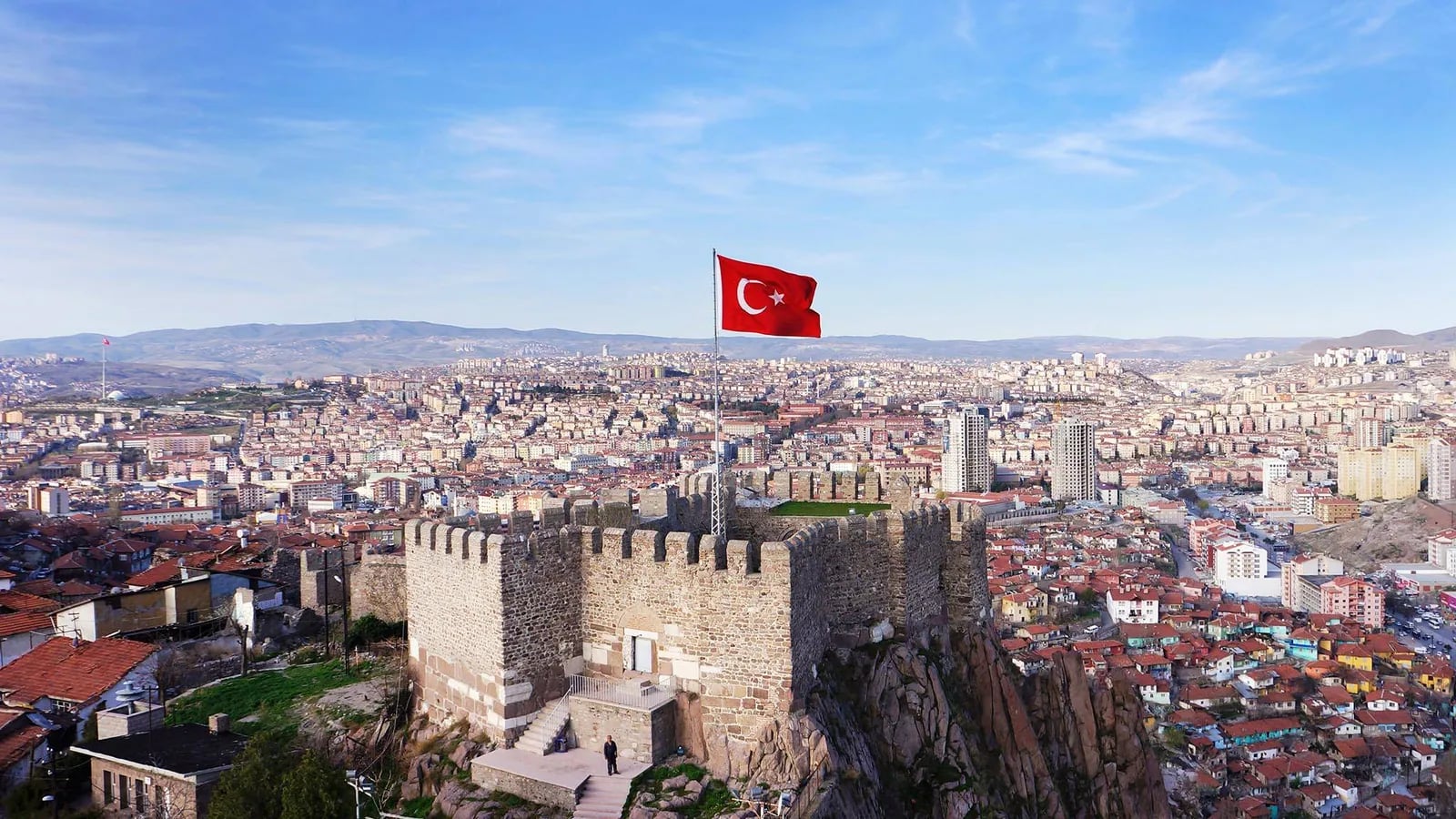 Ankara Kalesi surlarında Türk bayrağı; arkada şehir manzarası