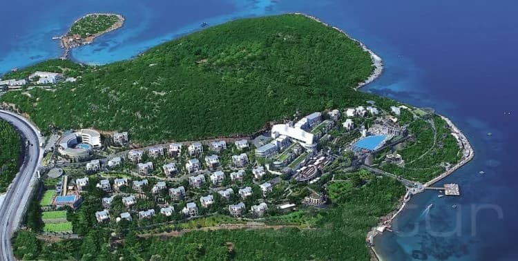 Yeşil yarımadaya yayılmış tatil köyü villaları ve koy, havadan