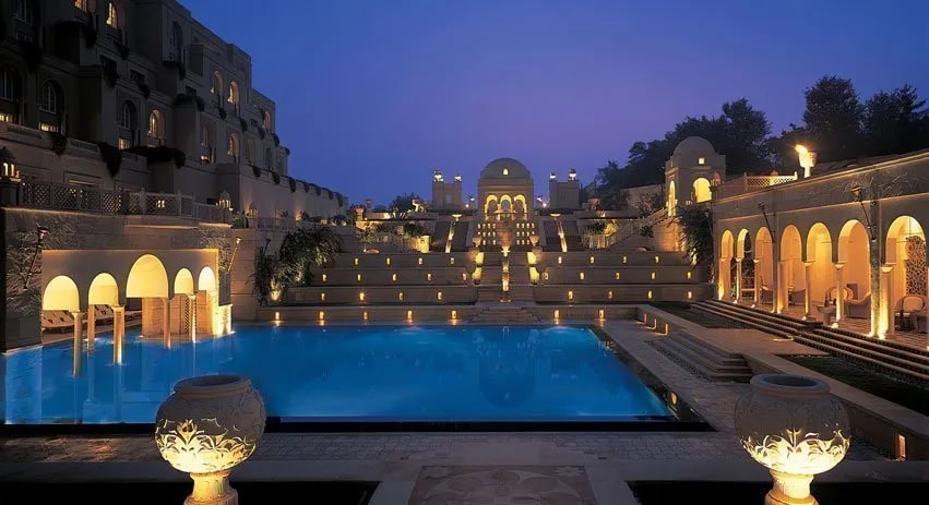 Gece aydınlatmasıyla geniş havuzu ve avlusu görünen bir resort