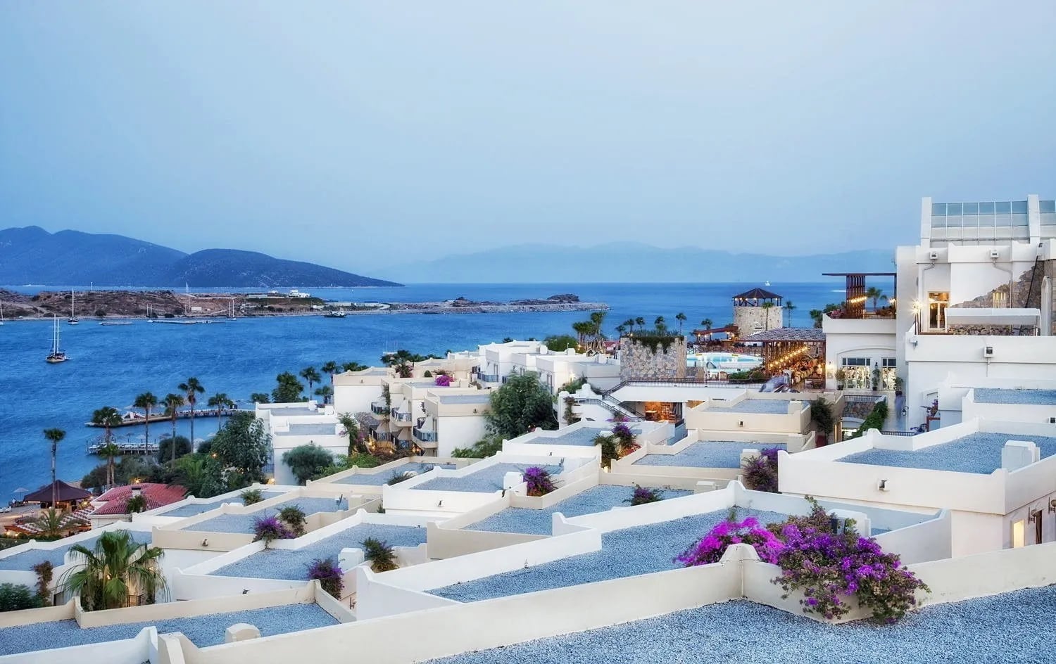 Alacakaranlıkta Bodrum: beyaz teraslı evler, begonviller ve körfezde demirlemiş yelkenliler