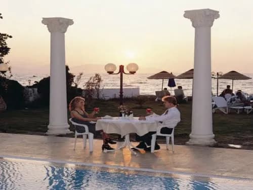 Sütunlu terasta deniz kenarında akşam yemeği masası