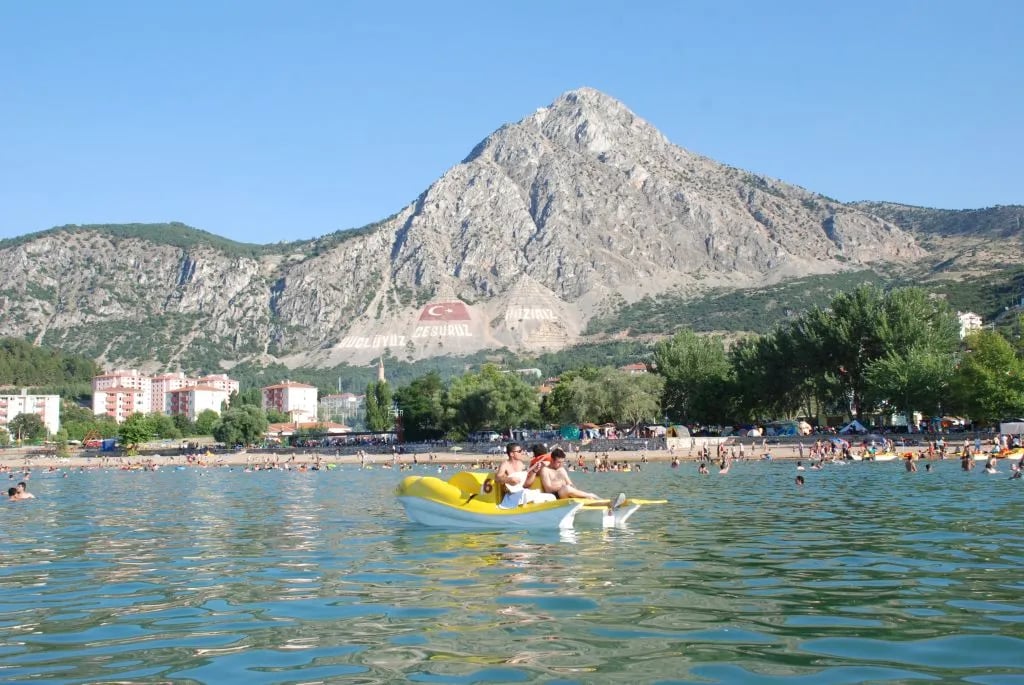 Eğirdir Gölü'nde deniz bisikletine binenler; arkada Sivri Dağ