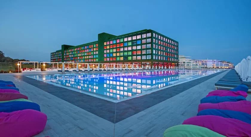 Adam & Eve Hotel'in yeşil camlı cephesi ve yansıma havuzu