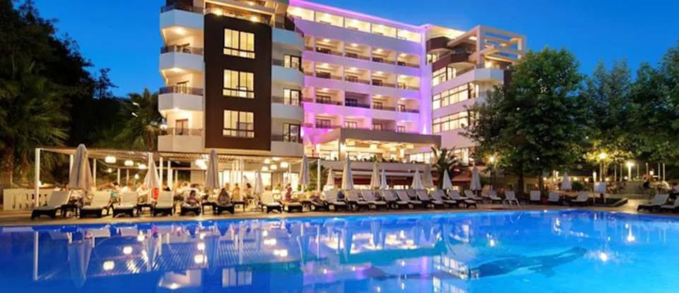 A'la Kum Hotel'in gece mor aydınlatmalı havuzu ve cephesi