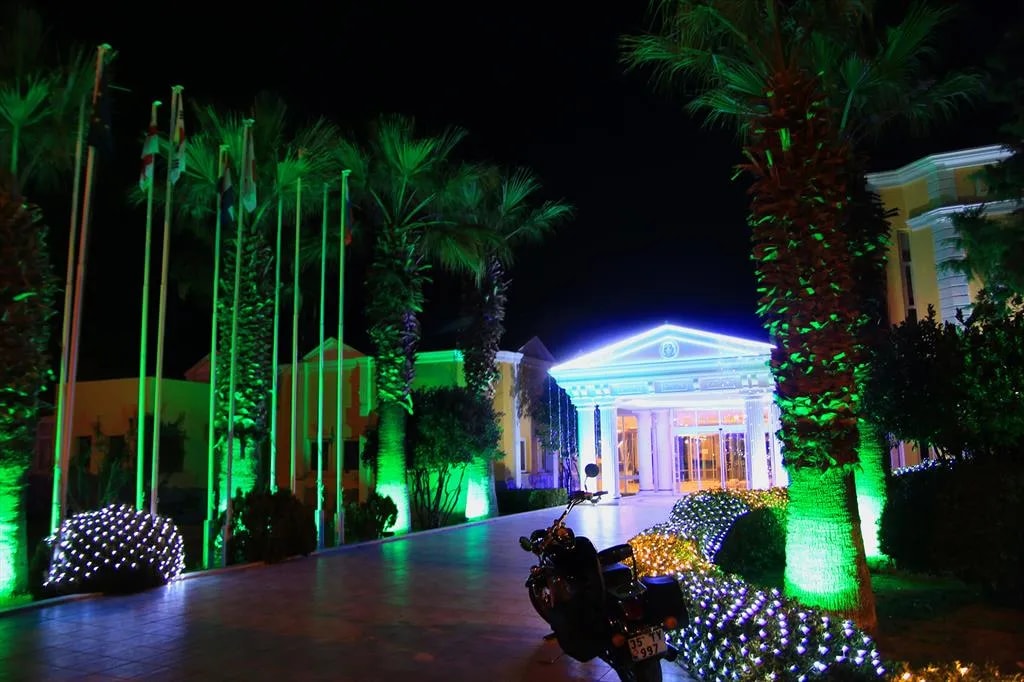 Gece yeşil-mavi ışıklarla aydınlatılmış sütunlu otel bahçesi