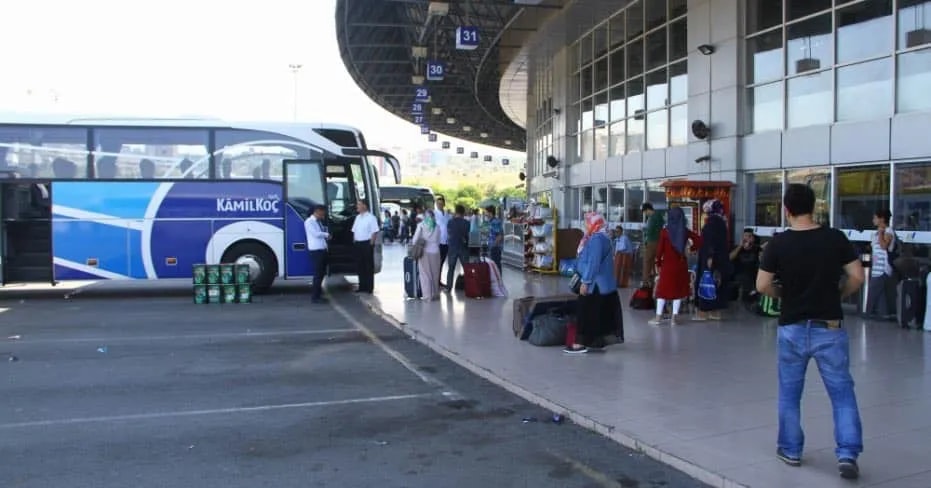 Otogar peronunda otobüs ve bavullu yolcular