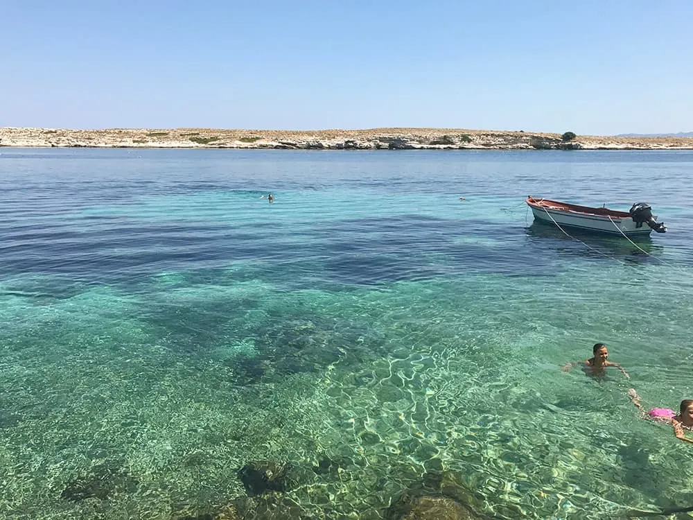 Karaburun kıyısında berrak deniz: demirli tekne ve yüzen iki kişi