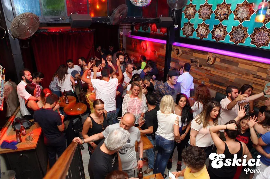Eskici barın kalabalık dans pisti; çini desenli duvar, disko topu ve ahşap masalar