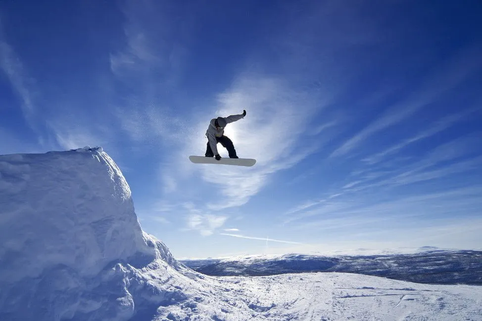 Karlı tepeden havalanan bir snowboardcu