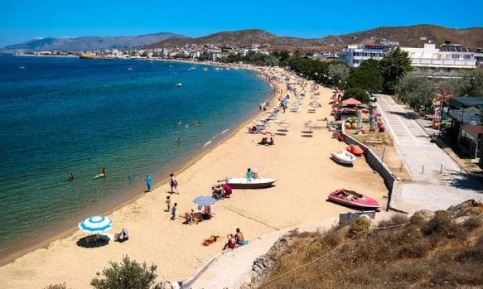 Avşa sahilinin uzun kumsalı: şemsiyeler, sığ turkuaz deniz ve sahil boyu yerleşim