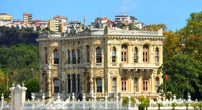 Boğaz kıyısında yoğun taş bezemeli iki katlı tarihî kasır ve beyaz bahçe parmaklığı