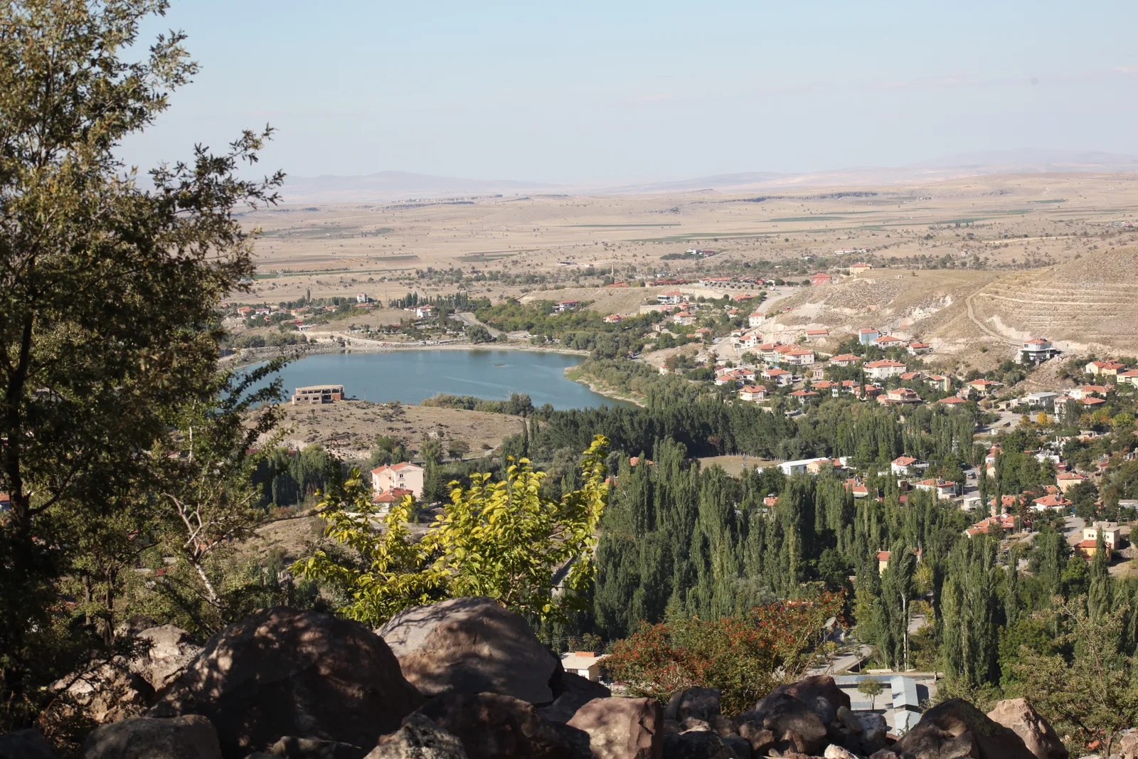 Helvadere ve göletine tepeden bakış; önde volkanik kaya blokları
