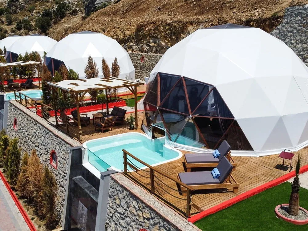 Her biri özel havuzlu ve şezlonglu beyaz dome çadırların üstten görünümü
