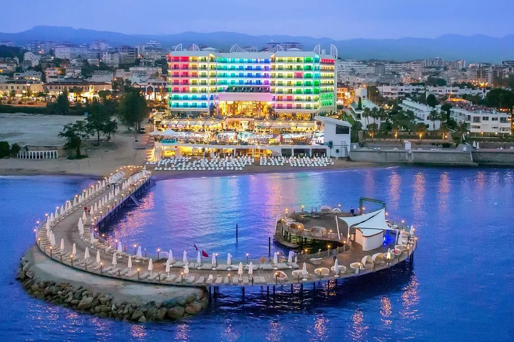 Renkli cephe aydınlatmalı otel, plajı ve denize uzanan yarım daire iskelesi